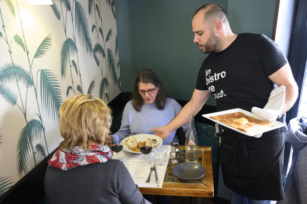 Un serveur sans masque de protection facial sert a manger a des clients dans le cafe restaurant salon le Java le jour de la levee des mesures pour lutter contre la pandemie de Coronavirus (Covid-19) ce jeudi 17 fevrier 2022 a Lausanne. (KEYSTONE/Laurent Gillieron)