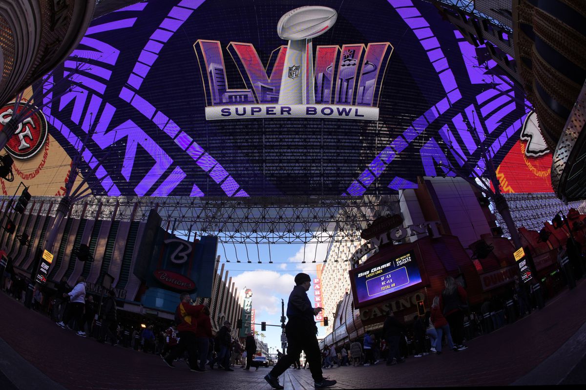 People cross a street at the Fremont Street Experience ahead of Super Bowl 58 Saturday, Feb. 10, 2024 in Las Vegas. The Kansas City Chiefs will play the NFL football game against the San Francisco 49ers Sunday. (AP Photo/Charlie Riedel)