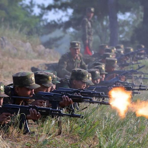 Nordkoreanische Soldaten trainieren an einer geheimen Basis der koreanischen Volksarmee, liegend mit Gewehren im Gras.