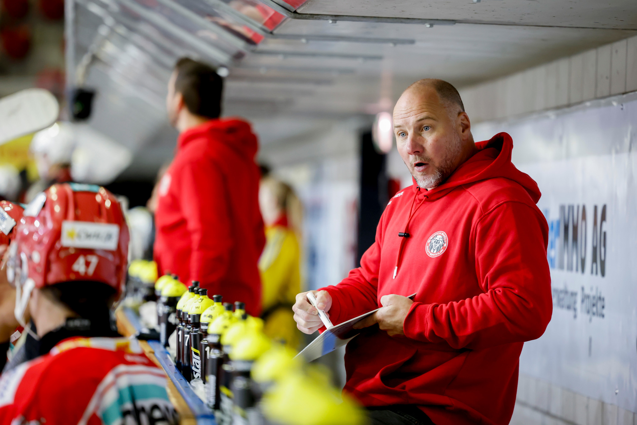 Winti-Trainer Frederic Rothen in roter Jacke spricht mit einem Spieler auf der Ersatzbank während des Chopfab Cups 2024 in der Eishalle Deutweg, Winterthur.