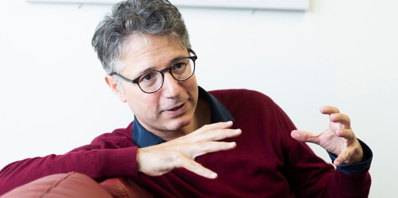 Le professeur Gilles Allali, spécialiste de la démence et de la maladie d'Alzheimer, assis sur un canapé rouge et gesticulant avec ses mains au Centre Leenaards de la Mémoire du CHUV à Lausanne, le 24 septembre 2024.