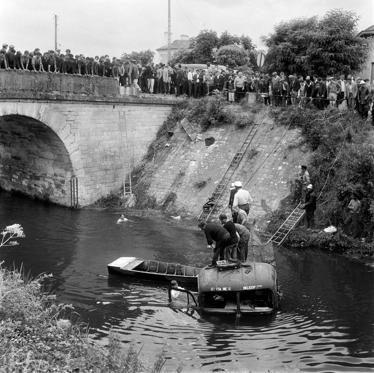 Divers look for survivors after a truck driven by a gendarme missed a curve and crashed into the crowd before plunging into a canal on July 11, 1964 in Port-de-Couze, a few minutes before the arrival of the riders of the Tour de France during the 19th stage between Bordeaux and Brive. According to witnesses, the truck which was carrying kerosene to refill helicopters, came in too fast and braked too late killing nine people instantly and  injuring dozens of others in the worst tragedy ever recorded on the Tour de France. Fifteen minutes later, the peloton arrived and stopped to pay respect to the victims before continuing the race. (Photo by AFP)