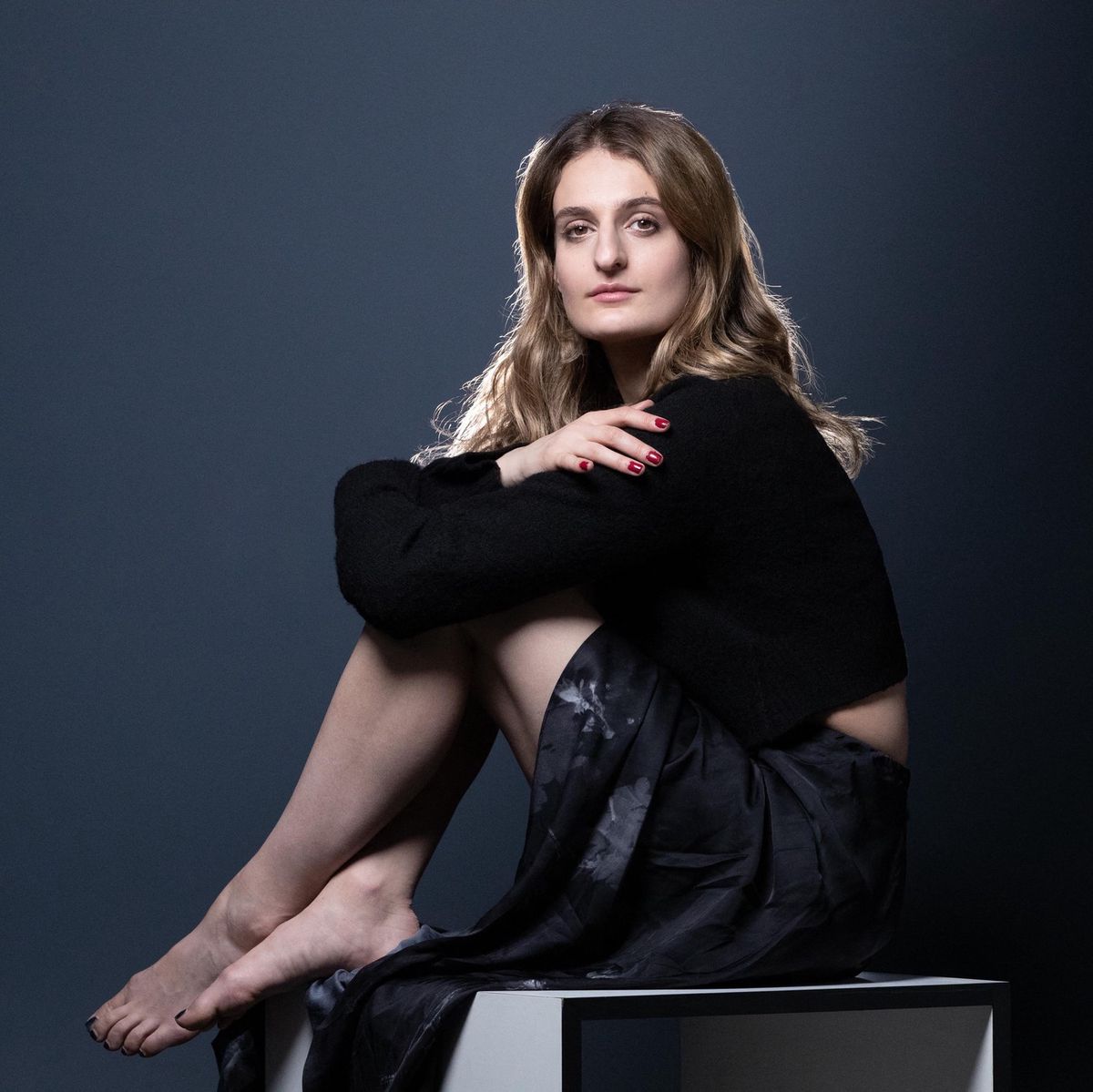 Gabriella Papadakis, médaillée d’or française en danse sur glace, pose assise avec un fond sombre, habillée en noir, Paris, 23 février 2022.