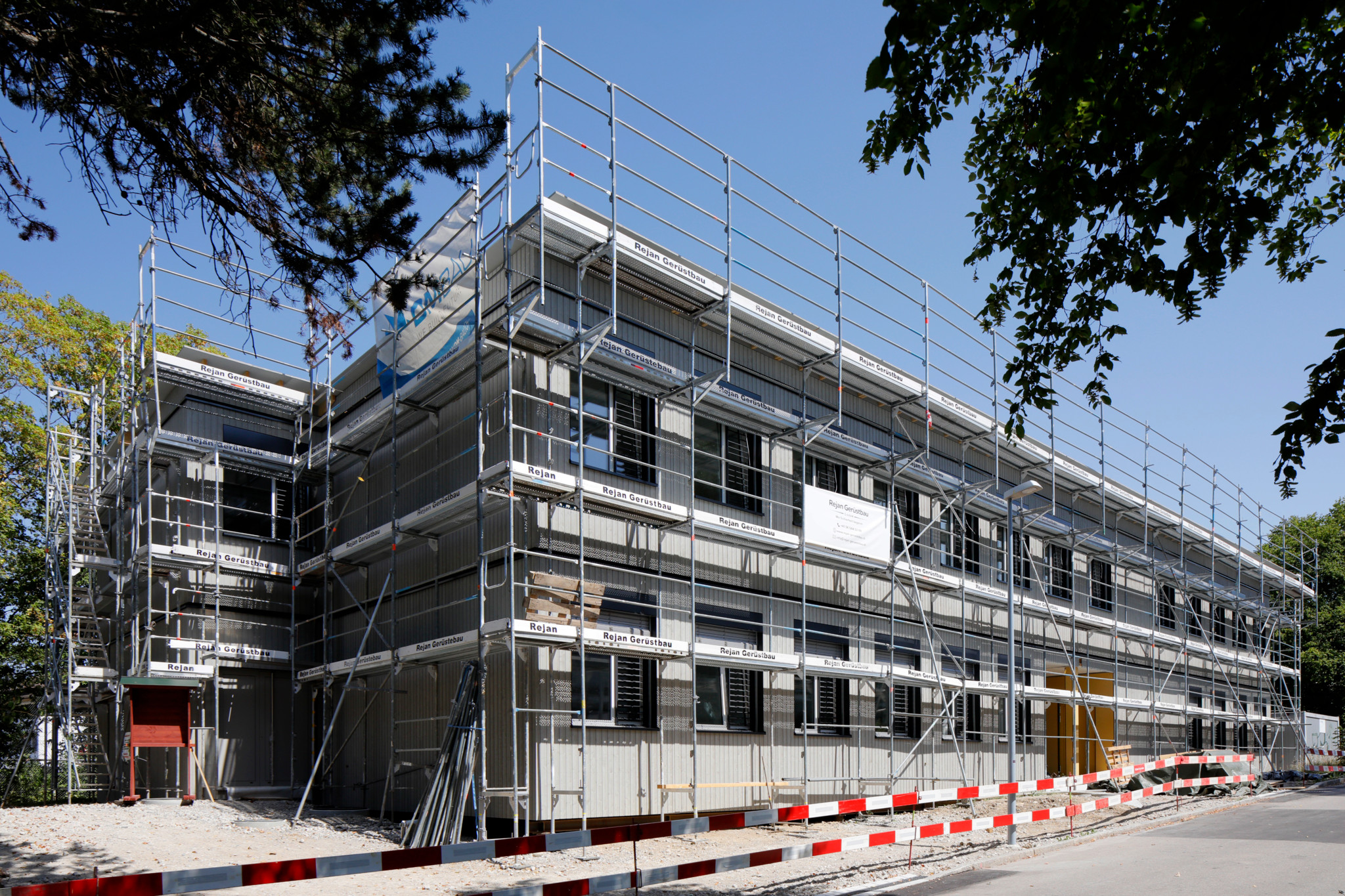 Provisorisches Betreuungshaus Rüterwis in Zollikerberg im Bau, eingerüstet und mit rot-weissem Absperrband gesichert.