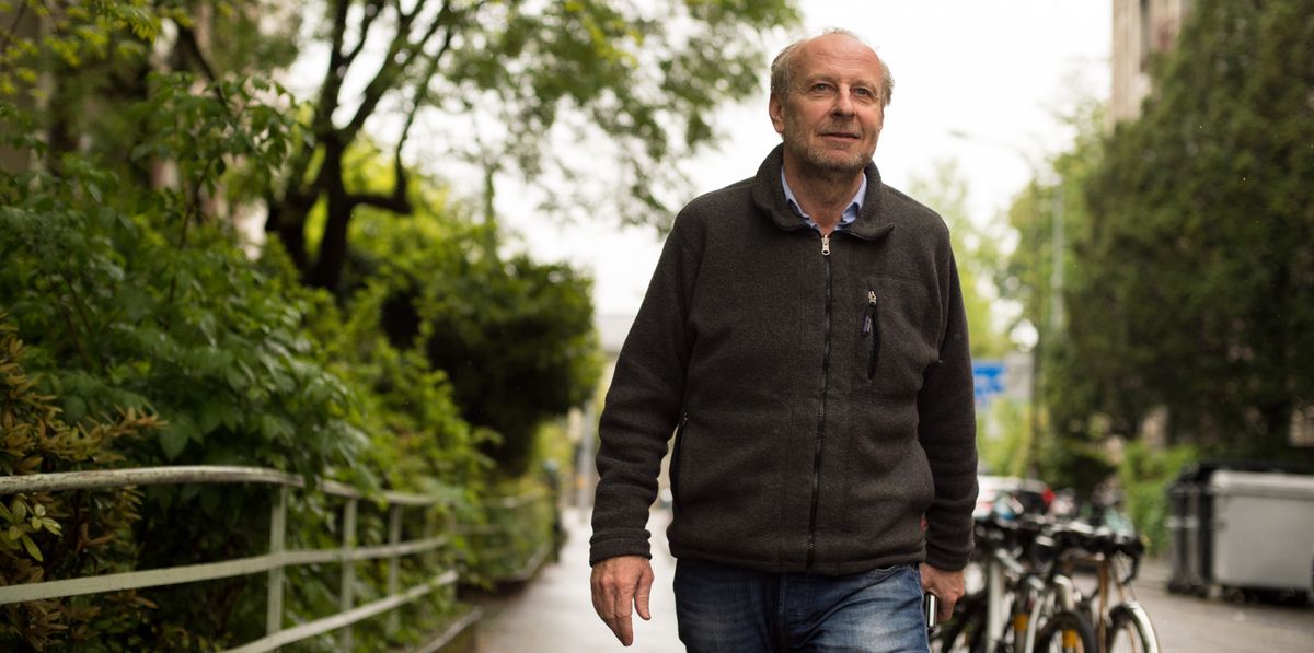 Yves Bouvier, marchand d'art, marchant dans une rue verdoyante de Genève sous un ciel gris le 10 mai 2021.