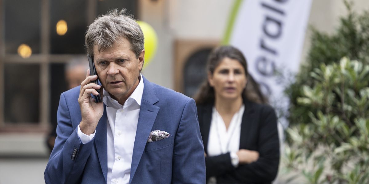 Juerg Grossen, président du parti Vert libéral téléphone devant le siège du parti Vert libéral. Une femme en arrière-plan.