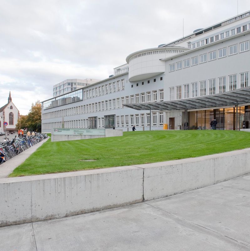 Universitätsspital Basel an der Spitalstrasse 21 mit grüner Rasenfläche und geparkten Fahrrädern im Vordergrund.