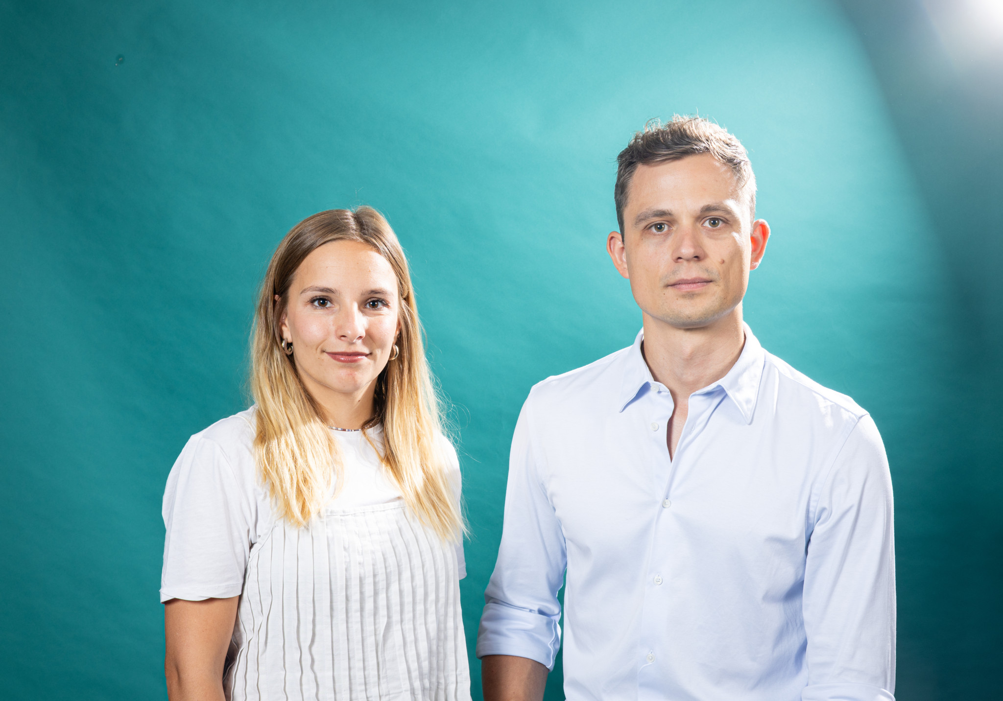 Sara Spreiter und Noah Fend, Teil der Tages-Anzeiger-Podcastcrew, vor türkisfarbenem Hintergrund in Zürich.