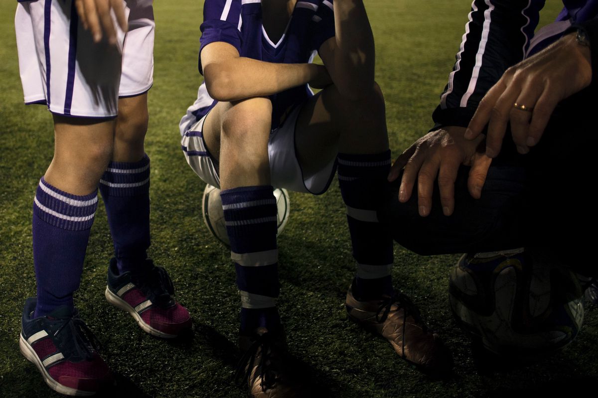 Une image montrant de jeunes joueurs de football écoutant les conseils d'un entraînteur.