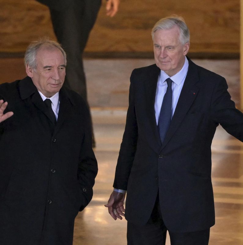 Francois Bayrou, à gauche, nouveau Premier ministre de la France, salue aux côtés de Michel Barnier à l’Hôtel Matignon à Paris.