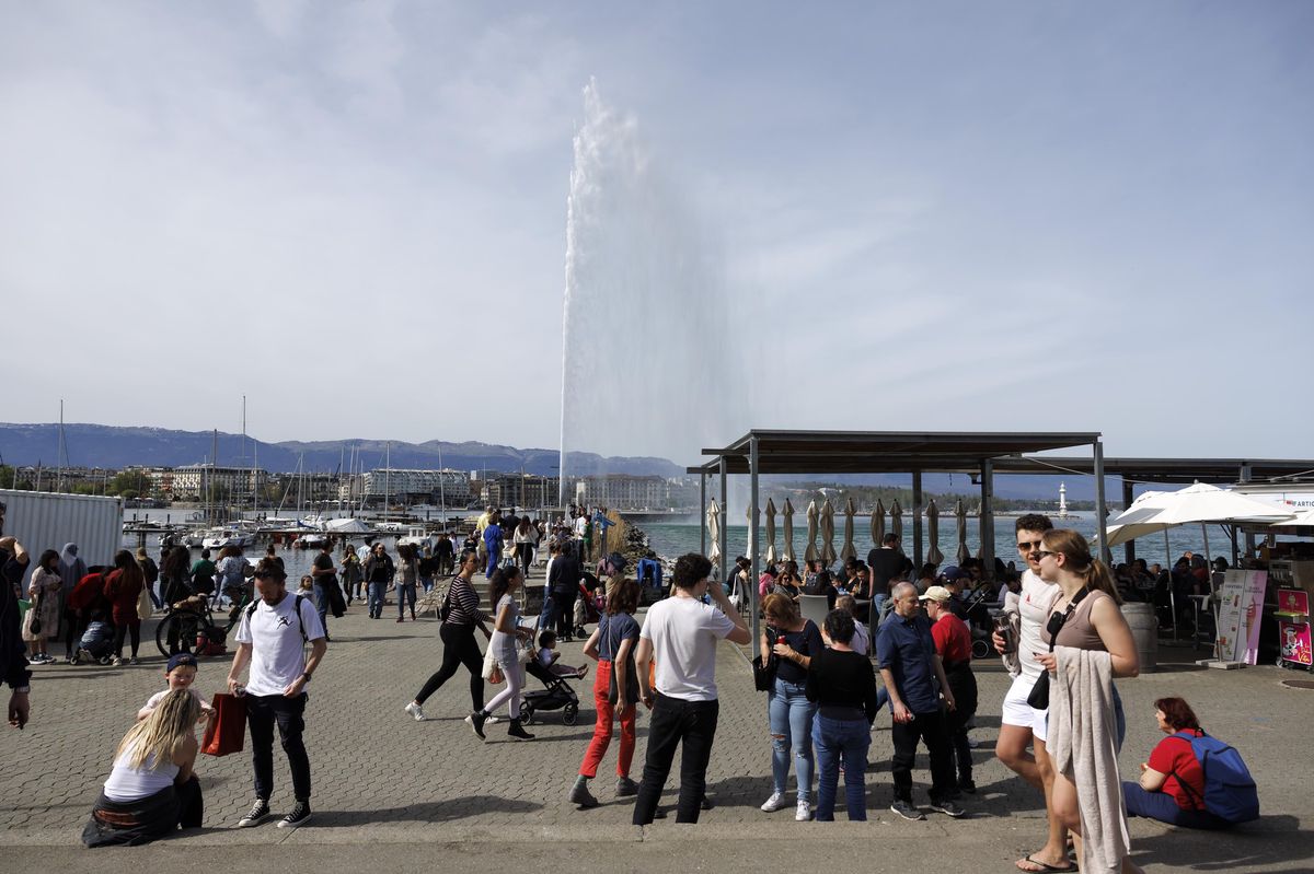 Des gens profitent du soleil printanier près du lac Léman à Genève, avec le jet d'eau en arrière-plan, le 6 avril 2024.