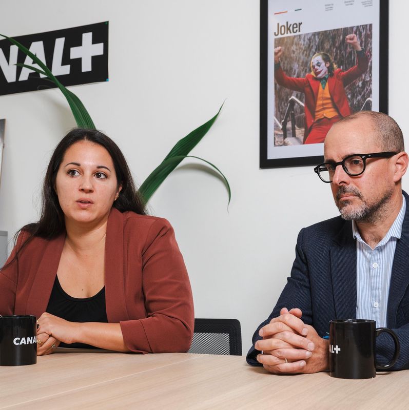 Myriam Rakib et Pascal Métral discutent des effets de l’IPTV sur les chaînes sportives à Lausanne, avec un décor Canal+ en arrière-plan.