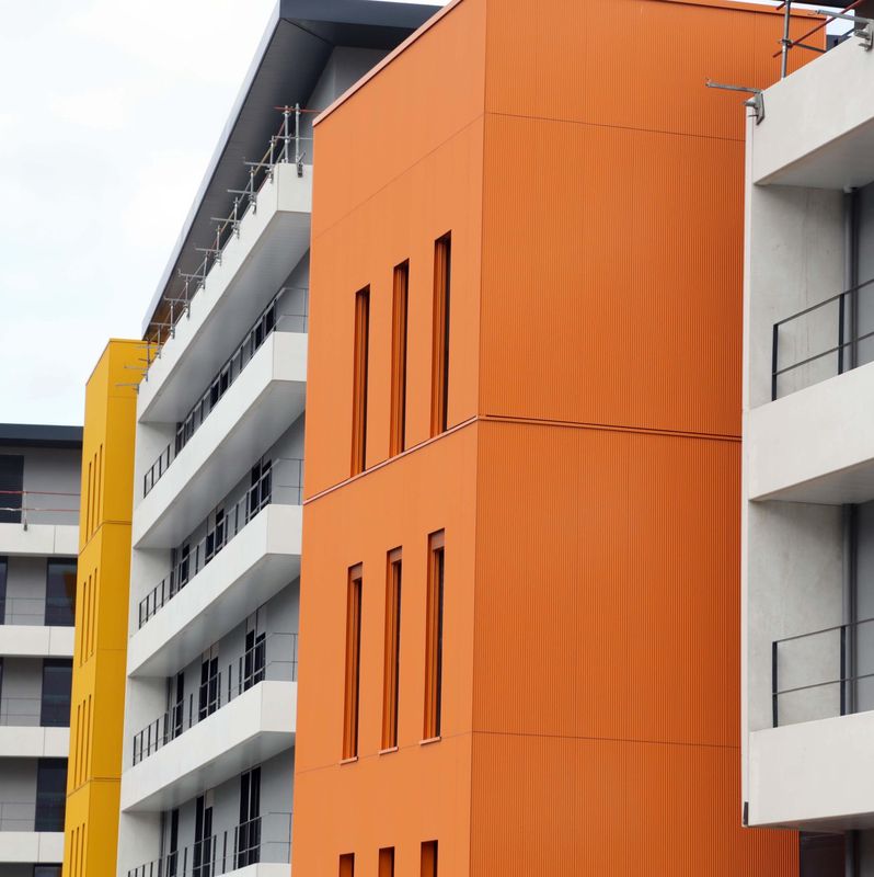 Façade colorée de l’Hôpital Privé Pays de Savoie avec des sections orange et jaune, photographiée par Lucien Fortunati.