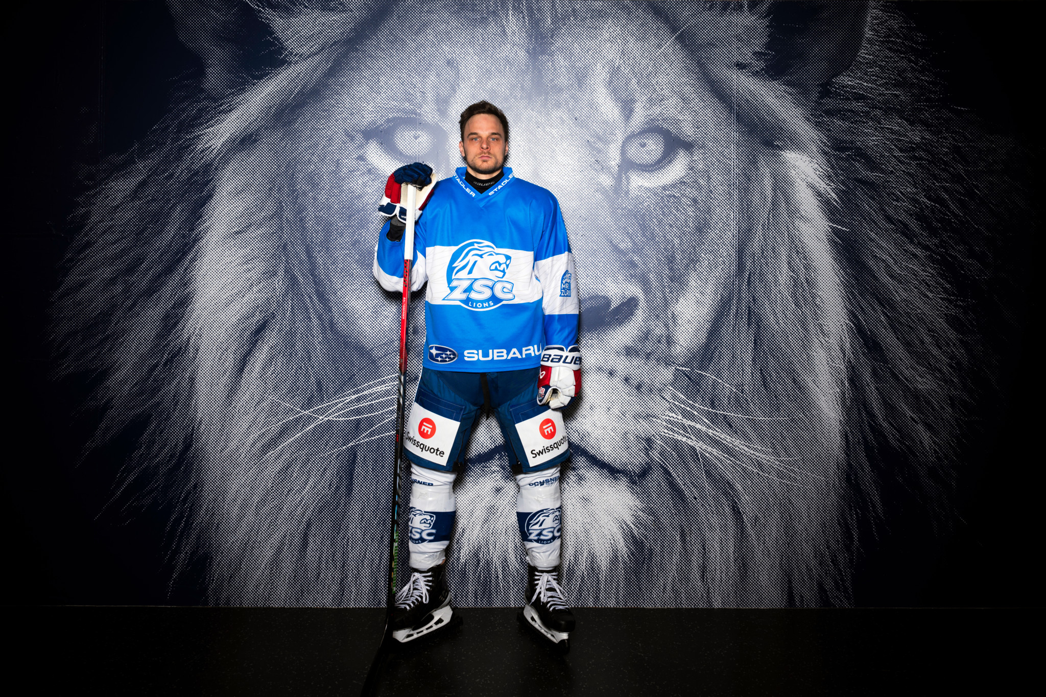 Chris Baltisberger, Stürmer des ZSC, in voller Eishockey-Ausrüstung vor einem Löwenmotiv in der Swiss-Life-Arena.