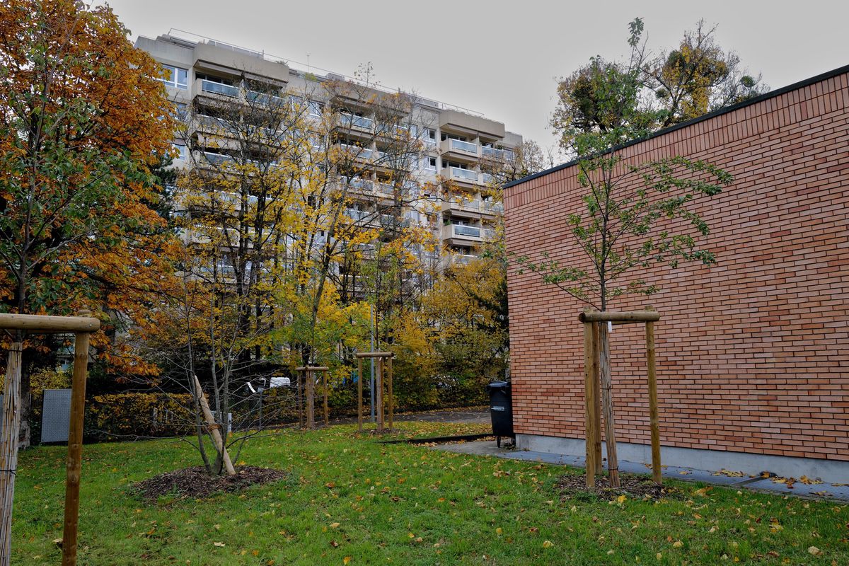 Vue extérieure de l’école Le Corbusier à Malagnou, Genève, avec des bâtiments temporaires devant un immeuble résidentiel.