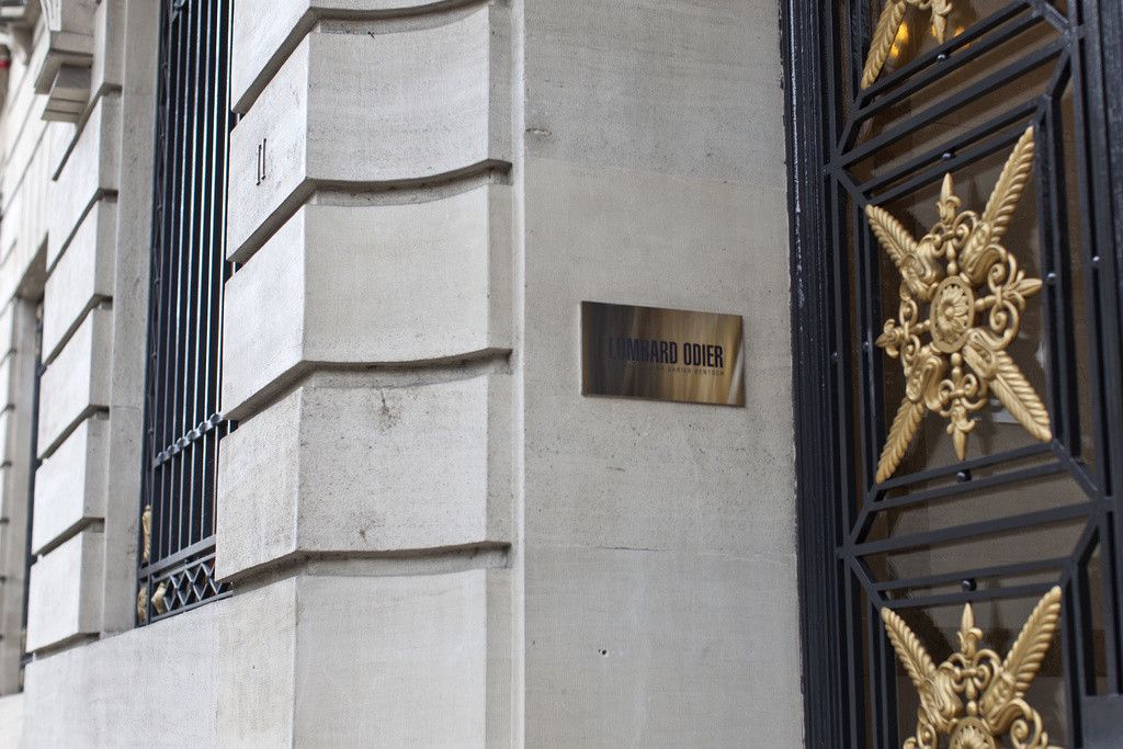 Plaque indiquant Lombard Odier à côté d'une porte ornée de symboles dorés.