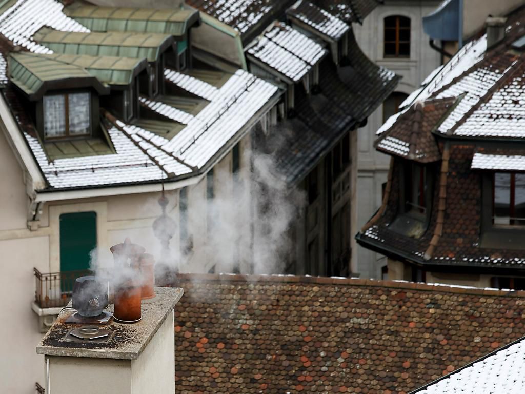Fumée s’échappant des cheminées sur des toits enneigés dans la Vallée de l’Arve, illustrant le problème des particules fines.