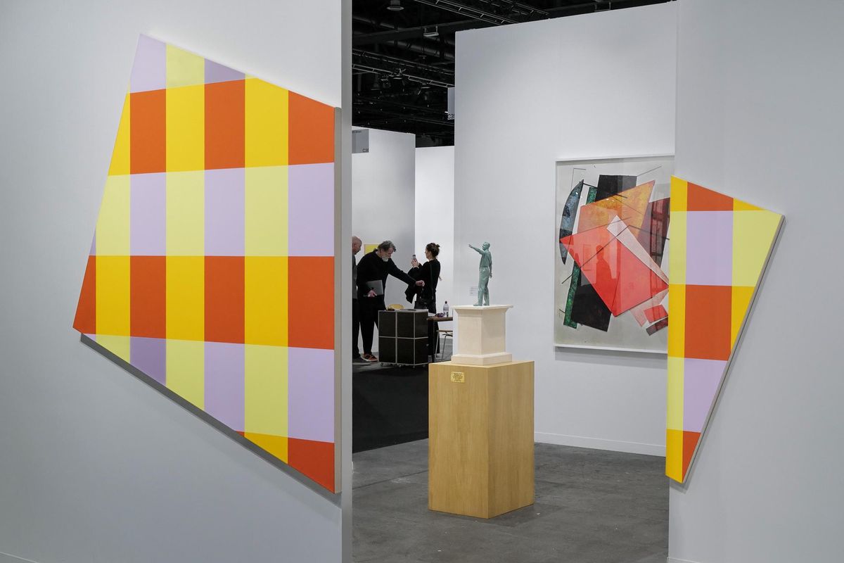 Exposition Art Genève à Palexpo avec des œuvres géométriques colorées et des visiteurs discutant.