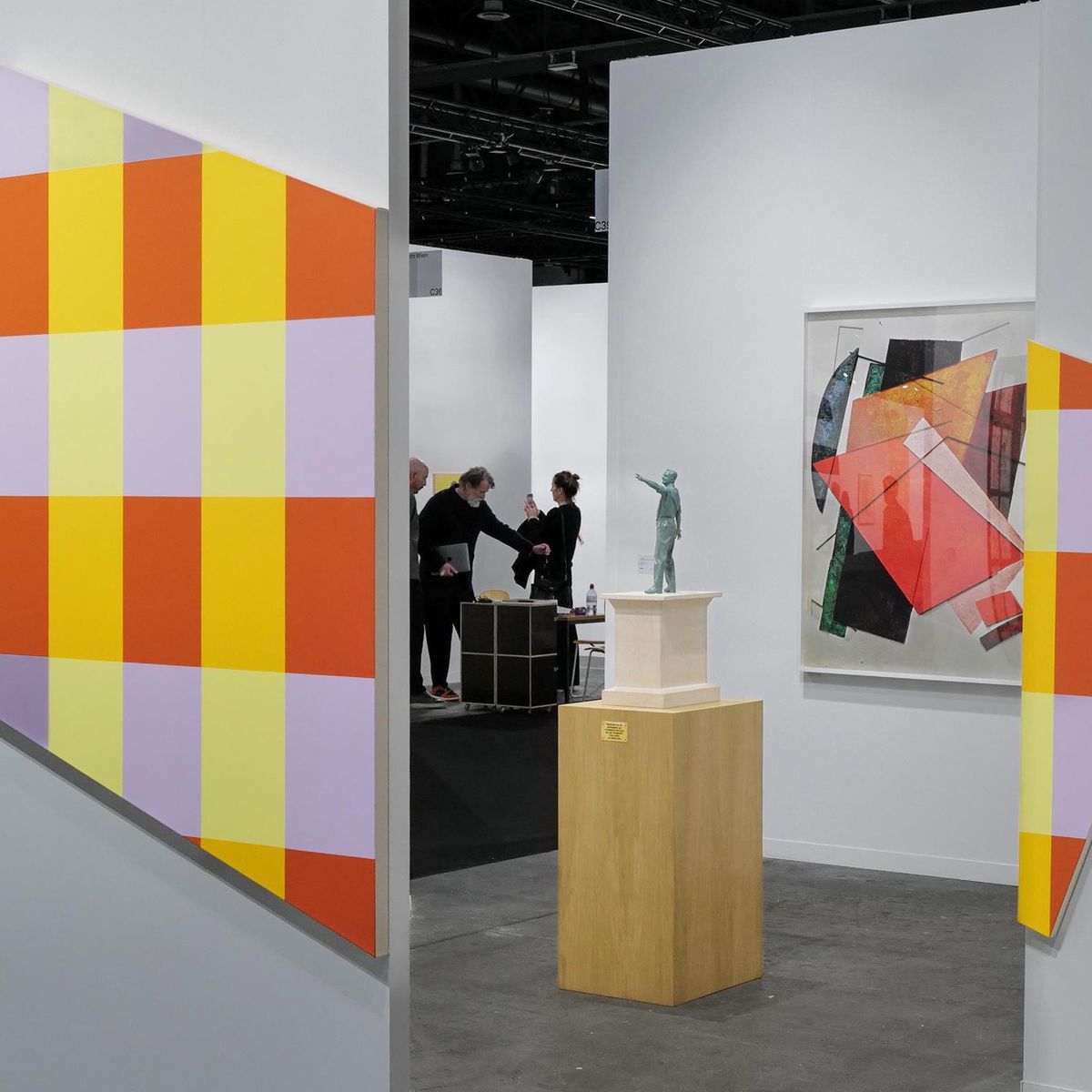 Exposition Art Genève à Palexpo avec des œuvres géométriques colorées et des visiteurs discutant.