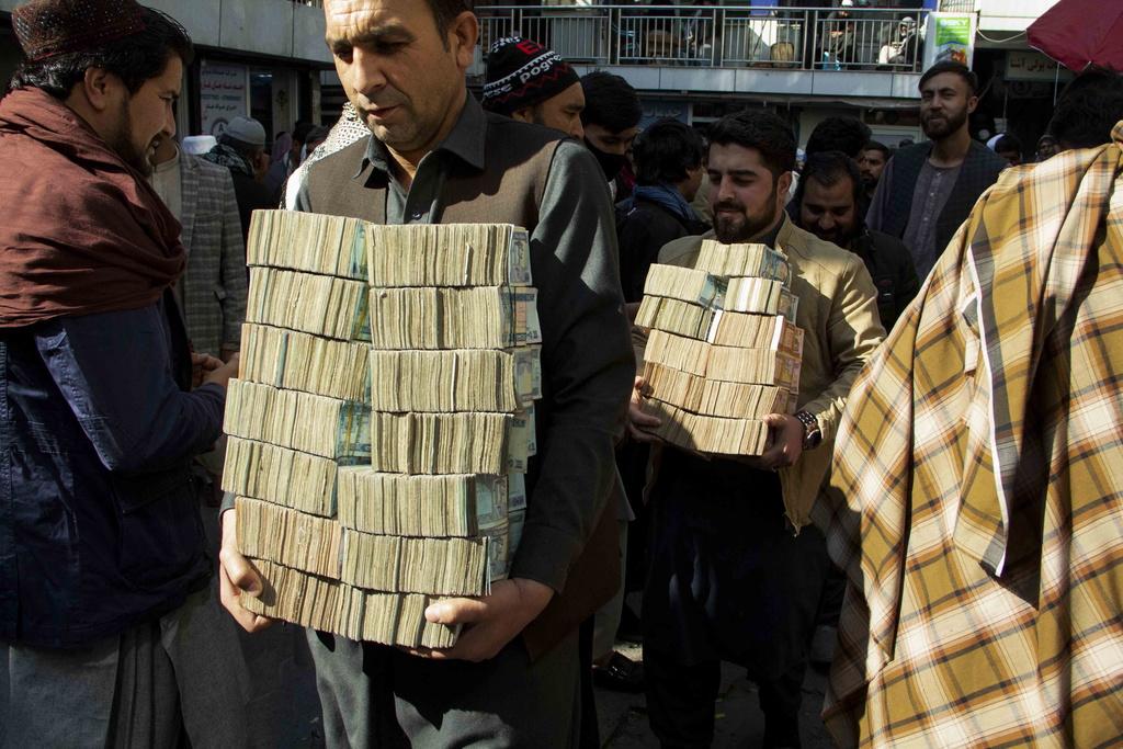 epa09569658 Afghan money changers sort currency at a market in Kabul, Afghanistan, 07 November 2021. The Taliban announced 03 November, a ban on foreign currencies in domestic transactions, a measure seeking to bolster the local currency, which after the Taliban's takeover of Afghanistan, touched its lowest value in 20 years. The Taliban's decision comes at a time of serious crisis for Afghanistan's financial system, which is on the verge of collapse after the United States froze about 10 billion US dollar of its funds following the Taliban takeover on August 15. EPA/STRINGER