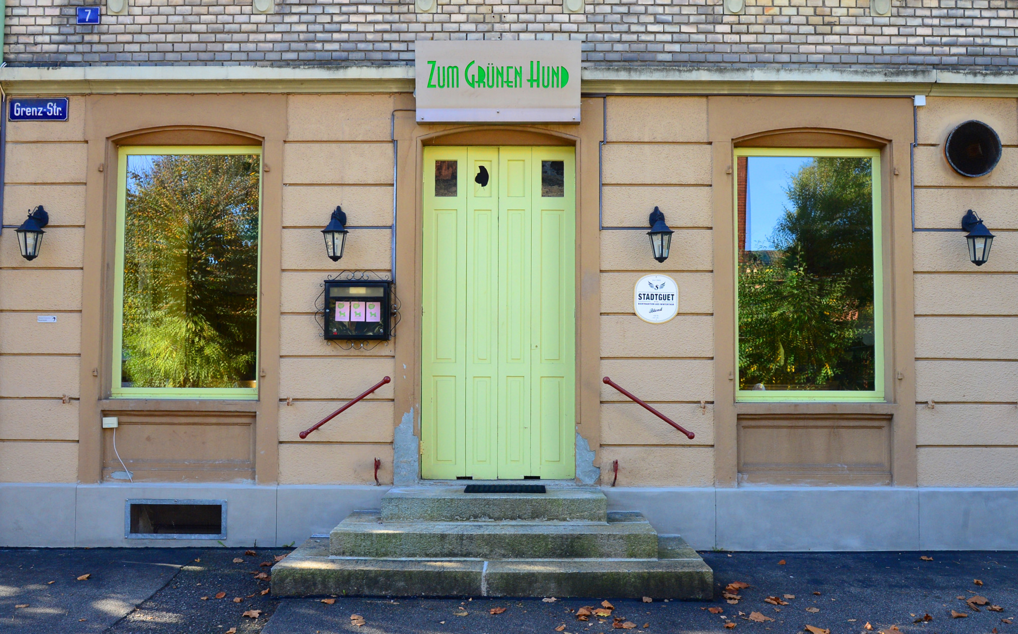 Eingang des Restaurants «Zum Grünen Hund» in Winterthur mit hellgrüner Tür und zwei grossen Schaufenstern.