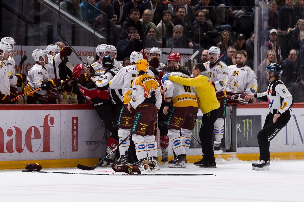 Teemu Hartikainen (GSHC) se fait soutenir par le physio, une flaque de sang sur la glace, pendant le match entre le Lausanne Hokey Club et le Geneve-Servette Hockey Club comptant pour le championat de National League, le mardi 27 fevrier 2024 a la Vaudoise Arena, a Lausanne (Bastien Gallay / GallayPhoto)
