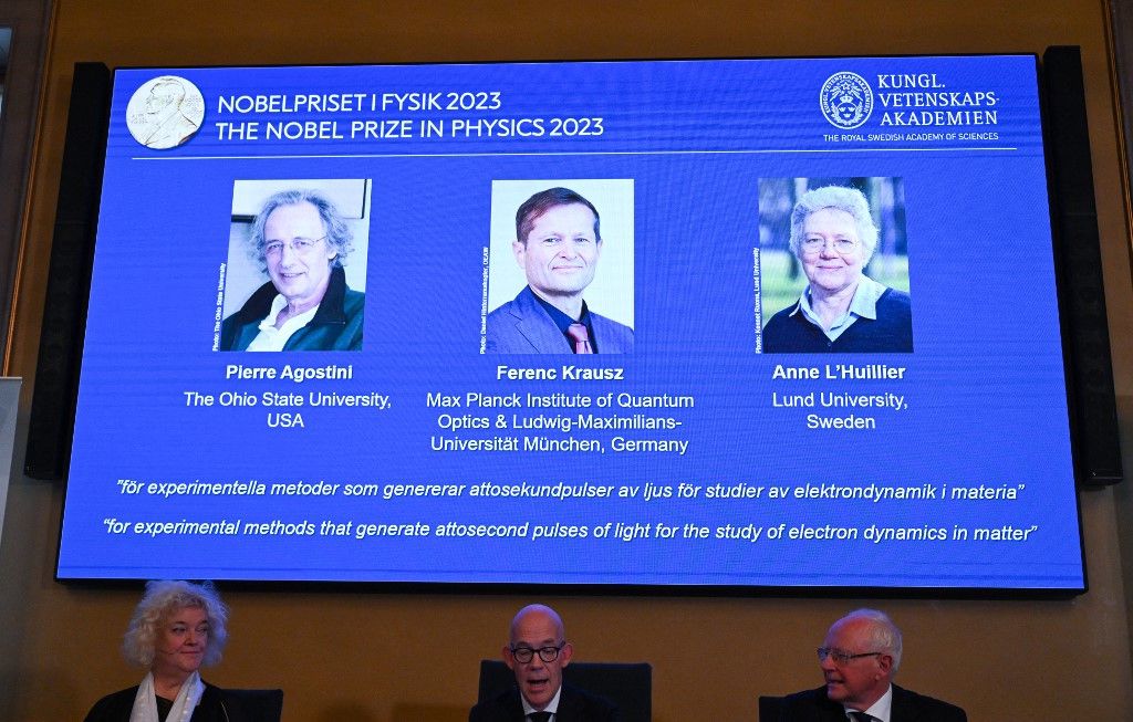 (L-R) US-based physicist Pierre Agostini, Hungarian-Austrian physicist and French physicist Anne L’Huillier appear on the screen as member of the Royal Swedish Academy of Sciences Chair of the Nobel Committee for Physics Eva Olsson, Secretary General of the Royal Swedish Academy of Sciences and Member of the Nobel Committee For Physics speak to the media during the announcement of the winners of the 2023 Nobel Prize in Physics at Royal Swedish Academy of Sciences in Stockholm on October 3, 2023. (Photo by Jonathan NACKSTRAND / AFP)