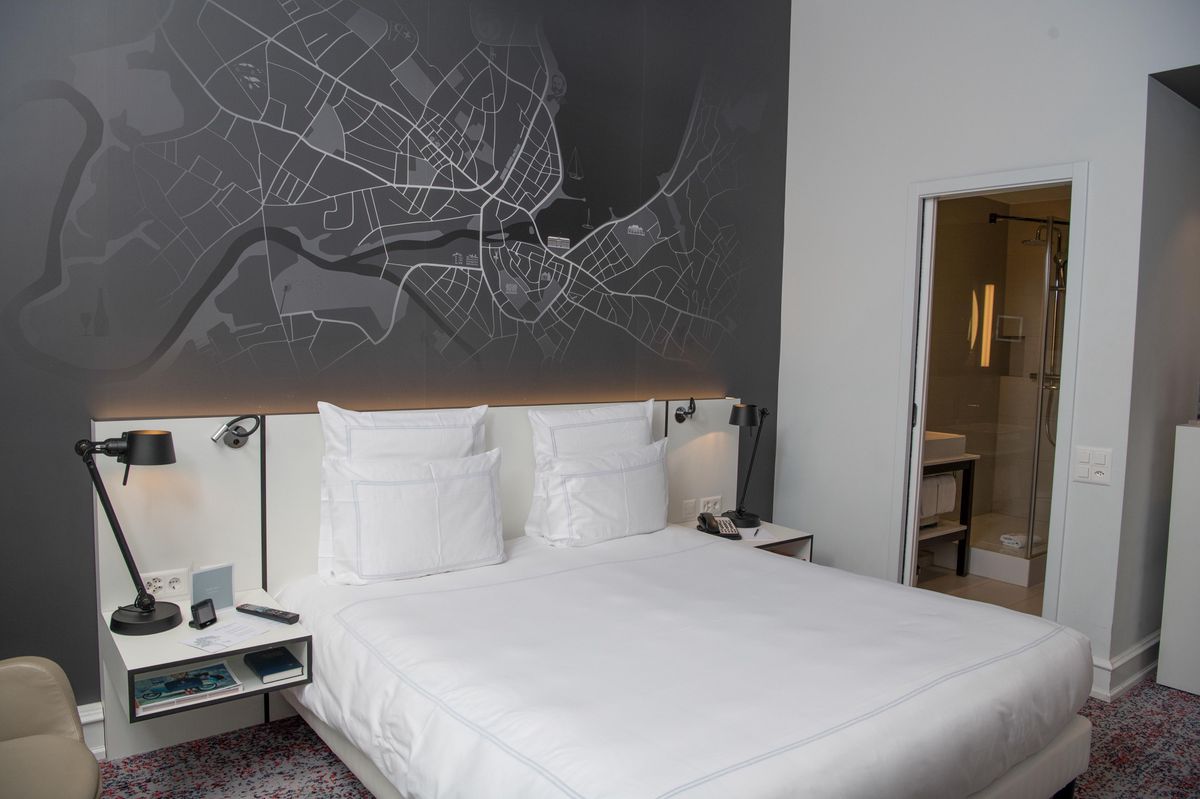 Chambre d'hôtel Metropole à Genève avec une carte murale en noir et blanc, lit double, et salle de bain adjacente.