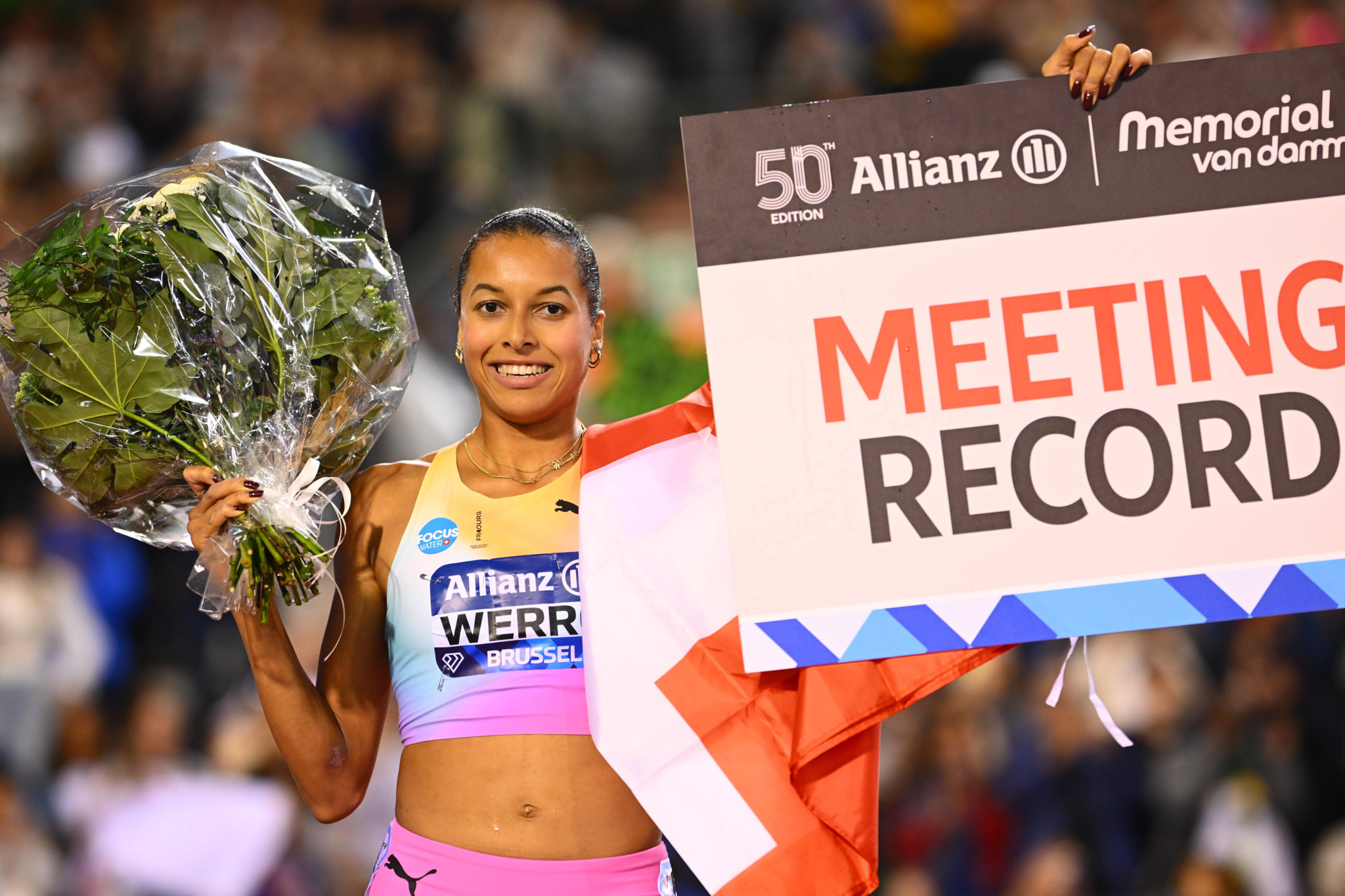 Audrey Werro hält einen Blumenstrauss und ein Schild mit «Meeting Record» beim Allianz Memorial Van Damme in Brüssel.