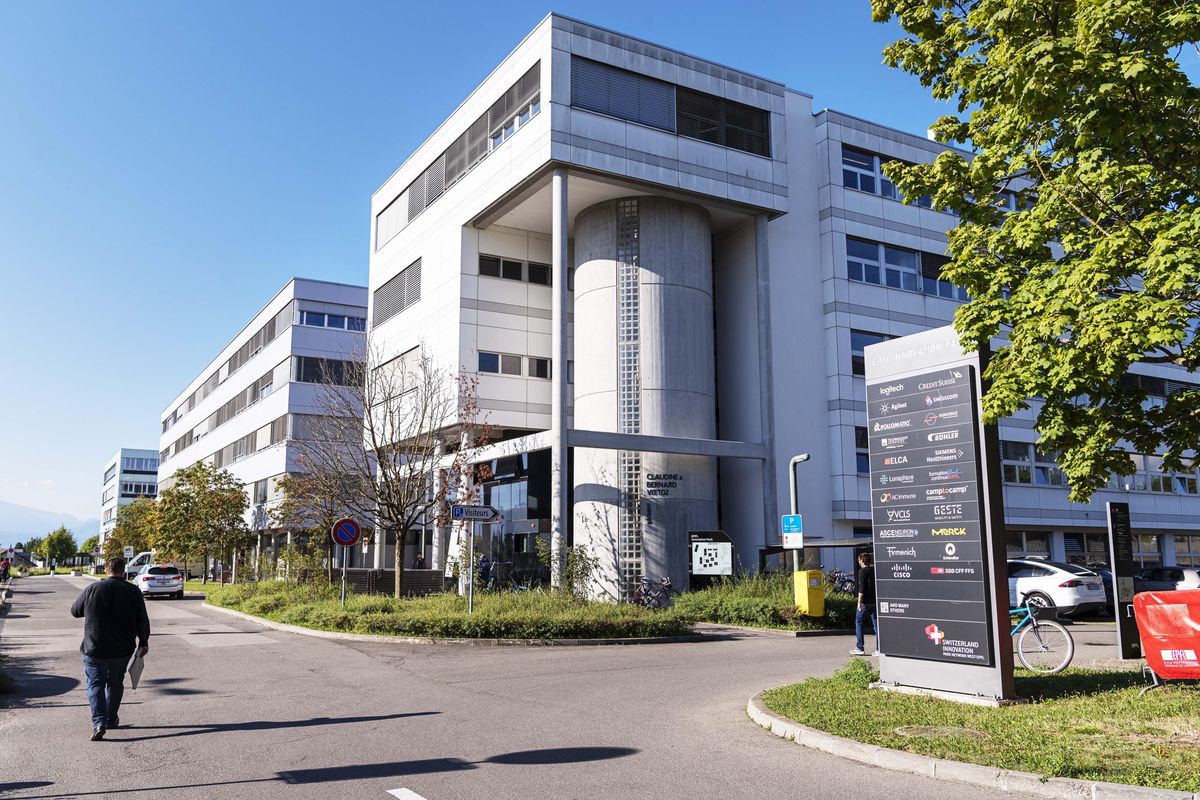 Bâtiment moderne de l'Innovation Park EPFL à Ecublens avec des enseignes d'entreprise et un ciel ensoleillé.