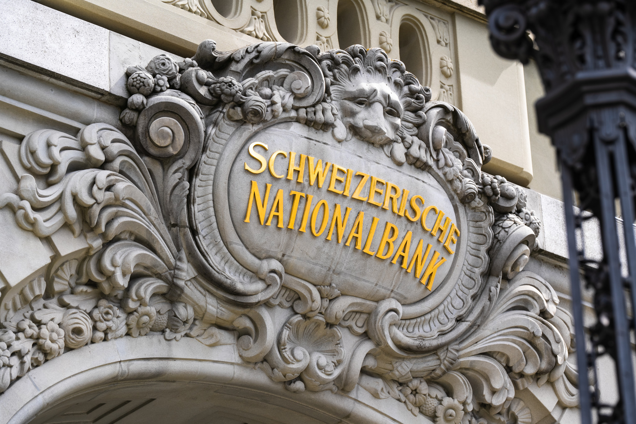 Das kunstvolle Eingangsportal der Schweizerischen Nationalbank in Bern mit einer goldenen Inschrift.