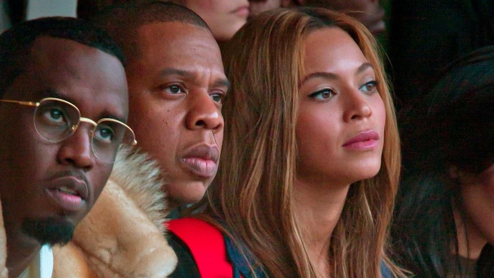 Drei Personen sitzen nebeneinander und schauen aufmerksam in eine Richtung. Sie tragen modische Outfits.