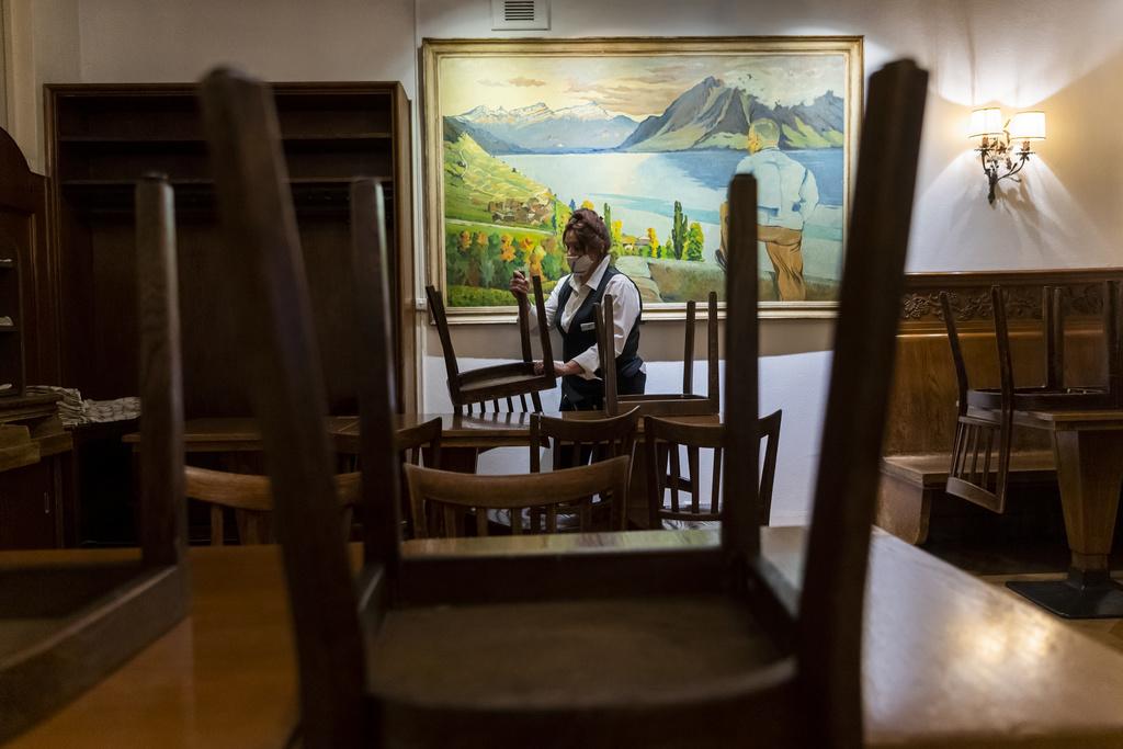 Eine Kellnerin stellt nach der Schliessung der Restaurants in Lausanne die Stühle auf die Tische. (3. Novemebr 2020)
