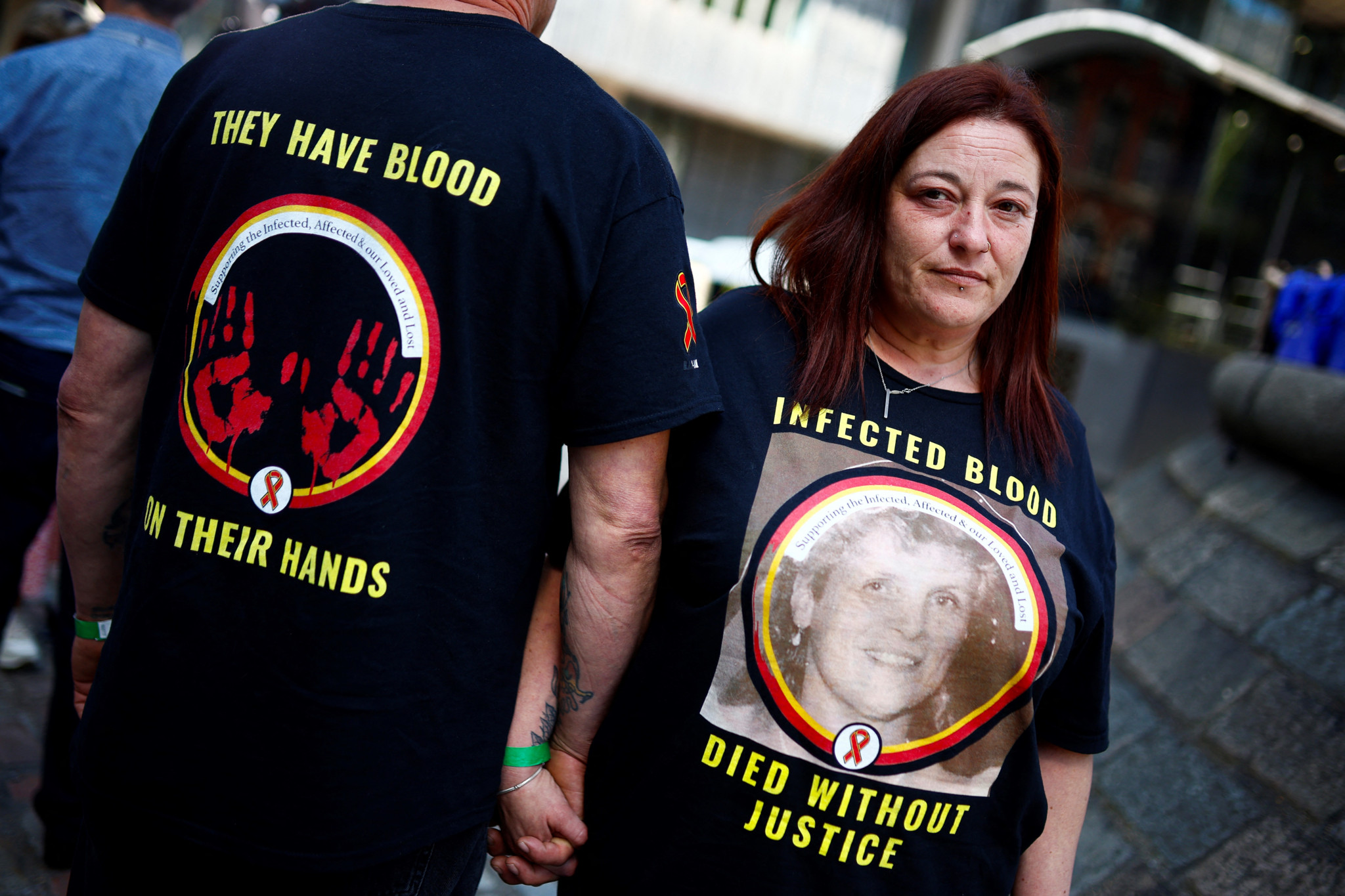 A relative of a victim wears a t-shirt reading "Infected blood, died without justice" as she stands outside Westminster, in central London, on May 20, 2024 during the Infected Blood Inquiry final report. A decades-long UK scandal in which thousands of people died after being treated with infected blood was covered up and largely could have been avoided, according to a bombshell report published on May 20, 2024. More than 30,000 people were infected with viruses such as HIV and hepatitis after being given contaminated blood in Britain between the 1970s and early 1990s, the Infected Blood Inquiry concluded. (Photo by BENJAMIN CREMEL / AFP)