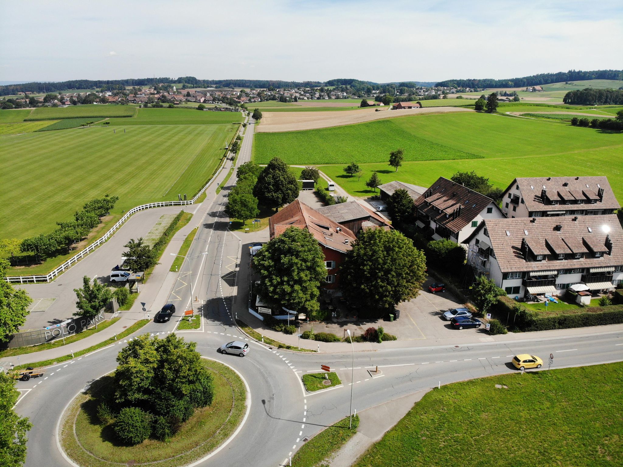Vogelperspektive auf den Kreisel und das Restaurant Wiesental in Unterohringen. Rechts davon stehen Mehrfamilienhäuser ähnlicher Façon. Im Hintergrund liegt Hettlingen. 