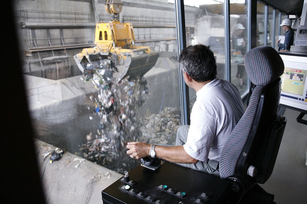 Opérateur contrôlant une grue à la station d’épuration des déchets des Cheneviers à Genève, déversant des détritus dans une trémie, le 3 août 2006.