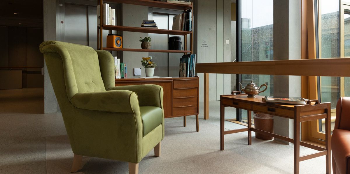 Salon à l'étage de l'EMS de AUbonne, le 27 septembre 2024, avec des meubles de seconde main chinés, comprenant une chaise verte, une étagère avec des livres et des plantes, et une petite table en bois.