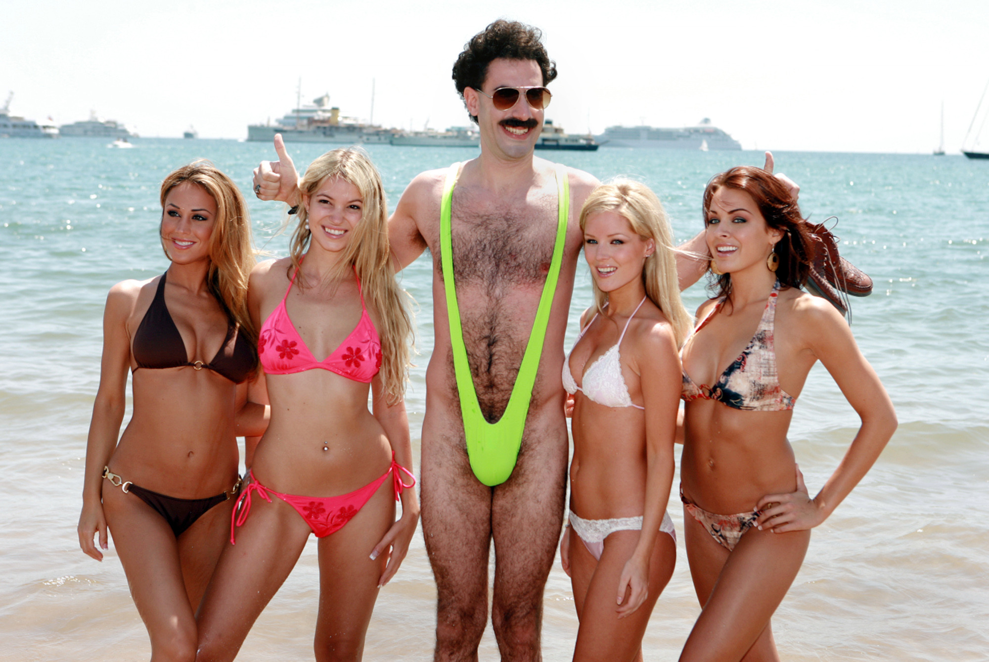 JAHRESRUECKBLICK 2006 - PEOPLE - USA FILM "BORAT" SACHA BARON COHEN: In einer Szene des Films "Borat" hat sich der kasachische Journalist Borat (Sacha Baron Cohen), Mitte, mit Strandschoenheiten umgeben, auf einem vom Verleih Fox herausgegebenen Foto, undatierte Aufnahme. Die Satire von und mit dem Star und Autor der Serie Da Ali G Show startet am Donnerstag, 2. November 2006, in den deutschen Kinos. (KEYSTONE/AP Photo/FOX/Str) === EDITORIAL USE ONLY, ===