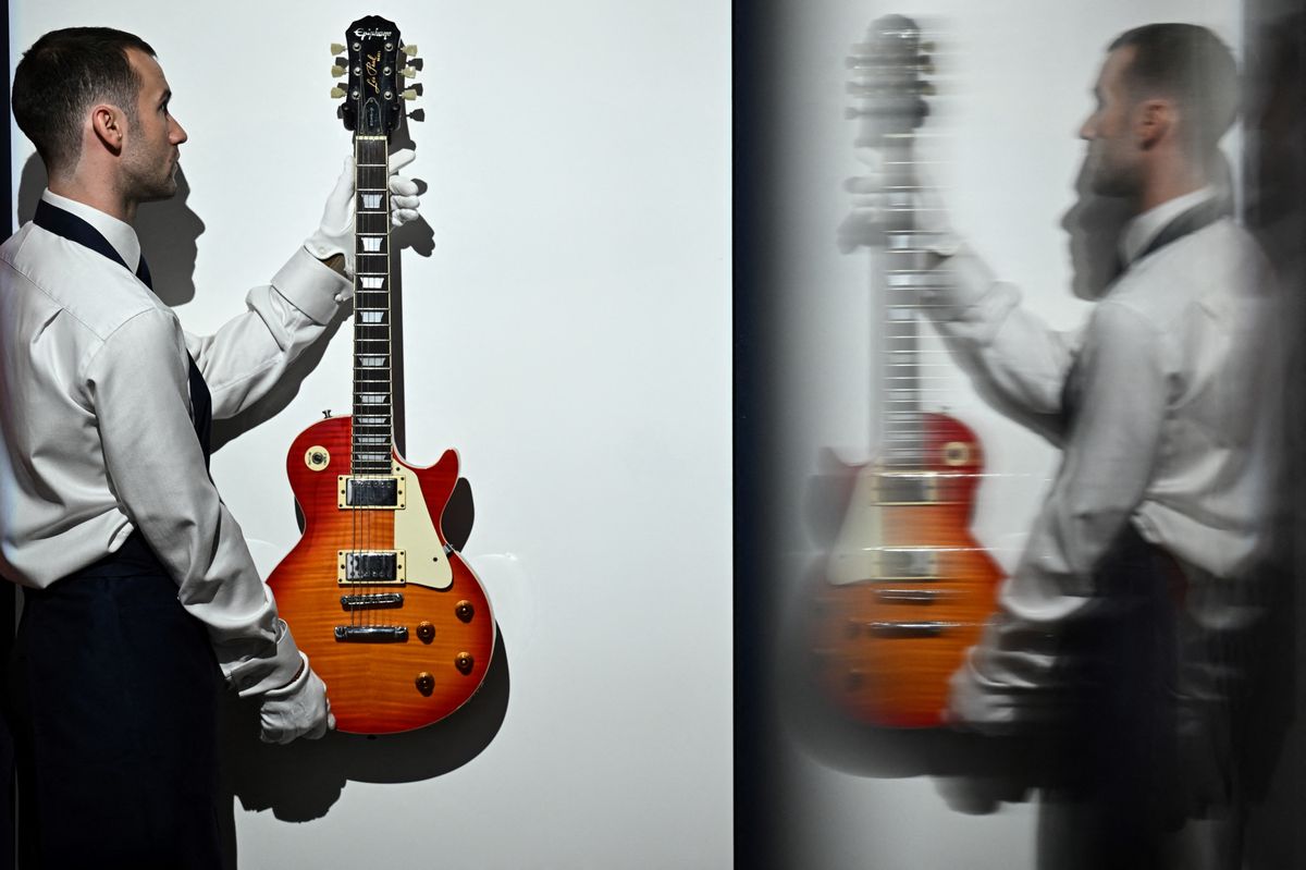 Un membre du personnel tient une guitare électrique Epiphone Les Paul ayant appartenu à Noel Gallagher du groupe Oasis, lors d'une conférence de presse chez Sotheby's à Londres le 9 septembre 2024.