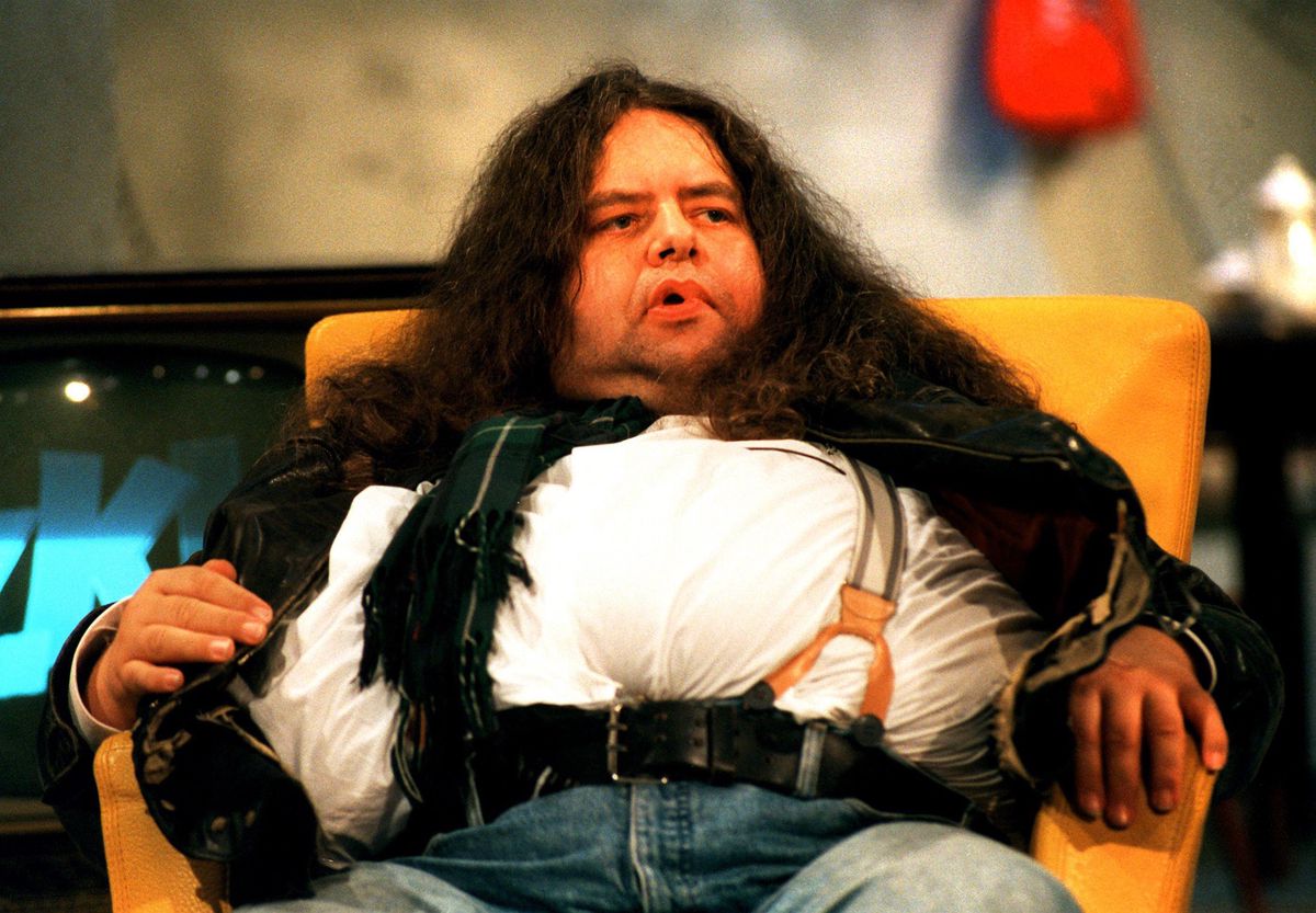 Österreichischer Moderator Hermes Phettberg in einer Talkshow in Frankfurt, 1995. Er sitzt in einem gelben Sessel.