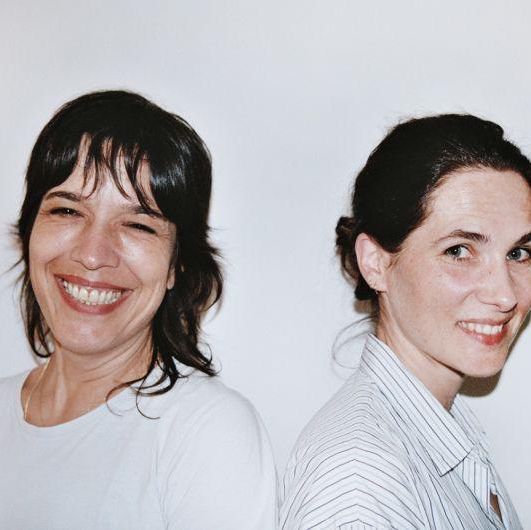 Deux femmes souriantes posent dans un cadre simple.