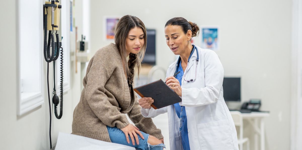 Une jeune adolescente est assise sur une table d'examen lors d'un rendez-vous médical de routine avec son médecin.