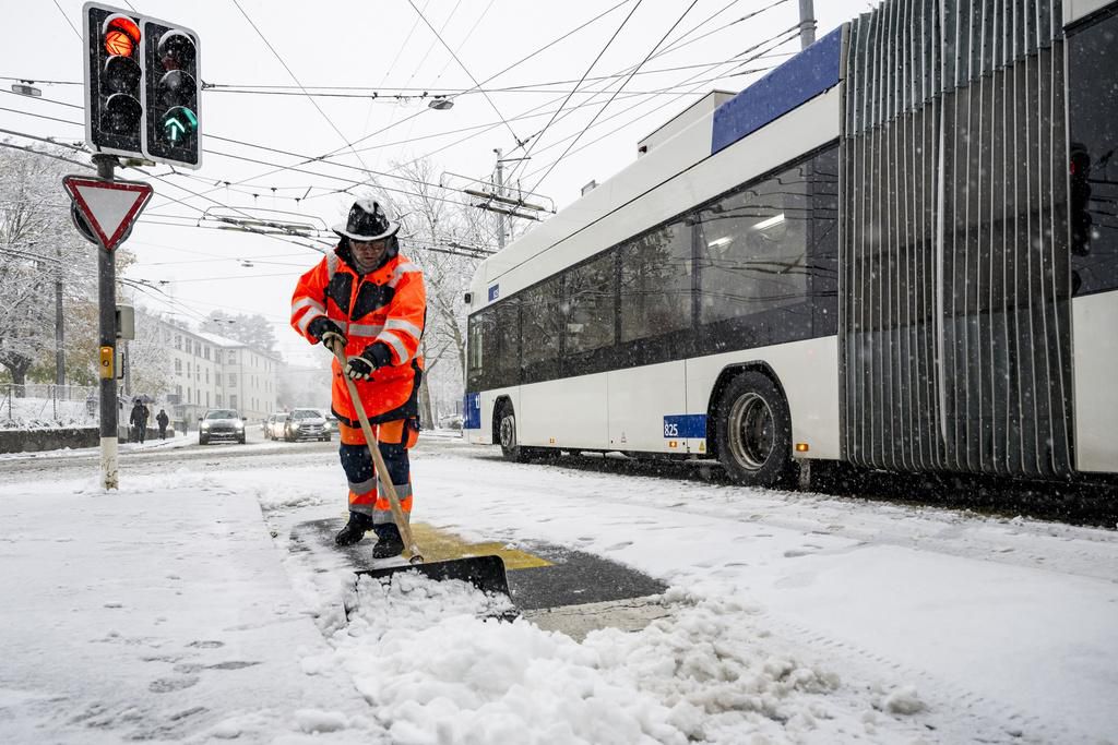Un employé de voirie enlève la neige devant un bus des TL à Lausanne lors des chutes de neige du 21 novembre 2024.