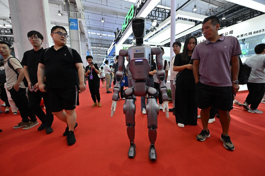 Menschen betrachten einen Roboter auf einer Ausstellung während der World Robot Conference 2025 in Peking.