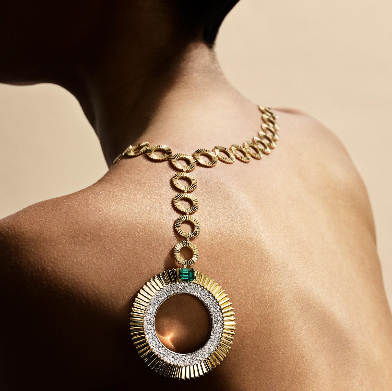 Collier en or avec pendentif circulaire sur l’épaule d’une personne.