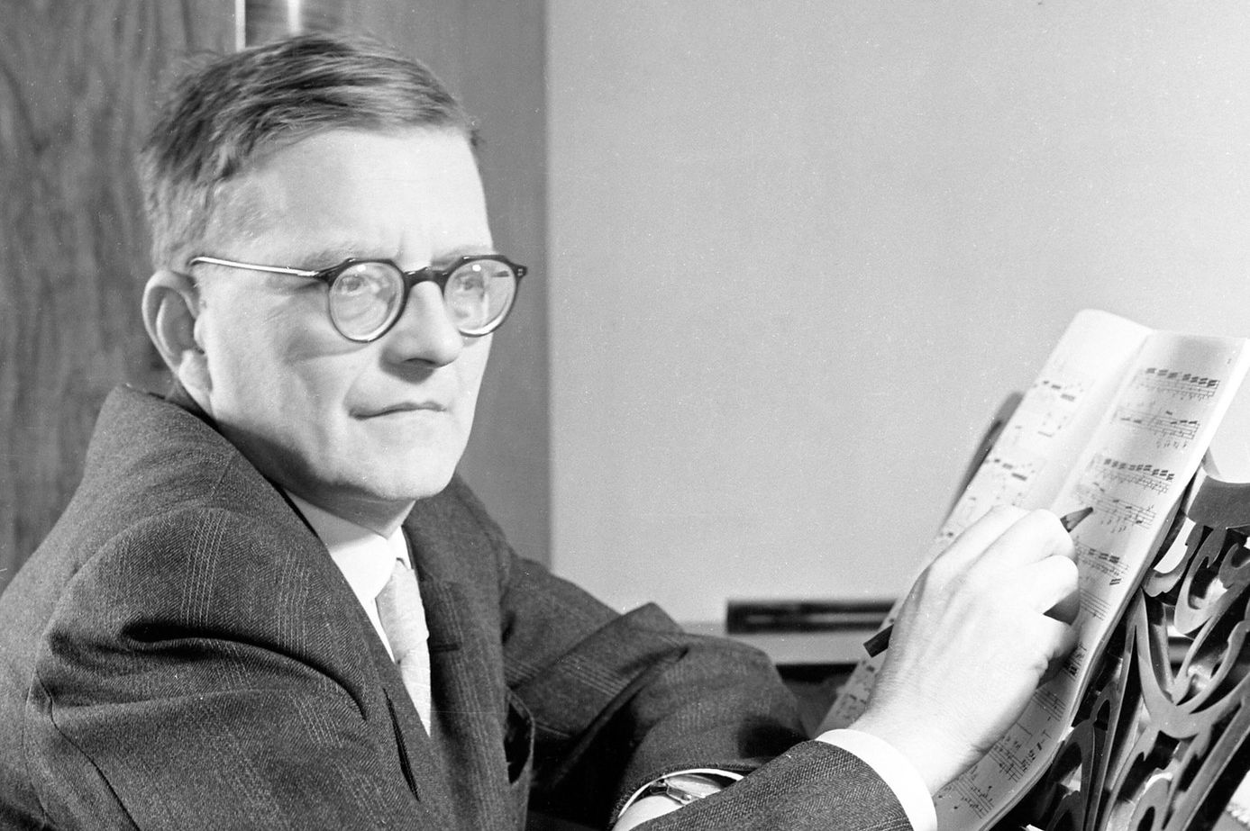 Compositeur soviétique Dmitri Chostakovitch en 1964 à Moscou, assis au piano avec une partition musicale.