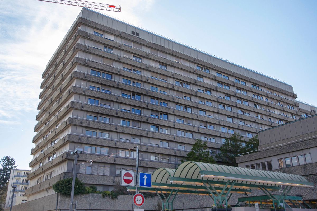 Bâtiment d'un hôpital à plusieurs étages avec une grue de construction visible en arrière-plan à gauche.