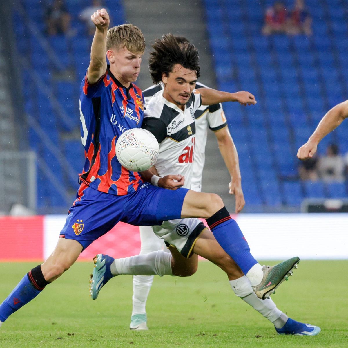 Fussballspiel in Basel: Anton Kade vom FC Basel in blau-rotem Trikot im Zweikampf mit Martim Alexandre Costa Marques von FC Lugano in weiss-schwarzem Trikot während der Super League am 27. Juli 2024. Fussballspiel in Basel: Anton Kade vom FC Basel in blau-rotem Trikot im Zweikampf mit Martim Alexandre Costa Marques von FC Lugano in weiss-schwarzem Trikot während der Super League am 27. Juli 2024.