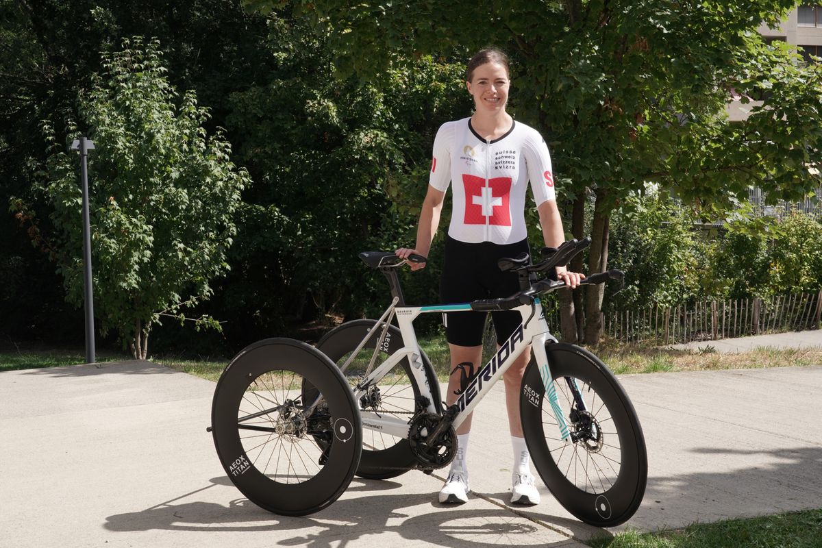 Céline van Till, vêtue d'un maillot de Swiss Olympic, pose avec son vélo avant les Jeux paralympiques à Lancy.