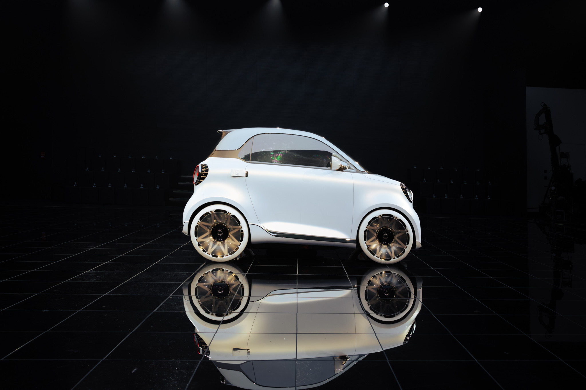 Weisses Smart #2 Konzeptauto mit goldenen Felgen auf dunkler Bühne, Nachfolger des ikonischen Smart For Two Weisses Smart #2 Konzeptauto mit goldenen Felgen auf dunkler Bühne, Nachfolger des ikonischen Smart For Two